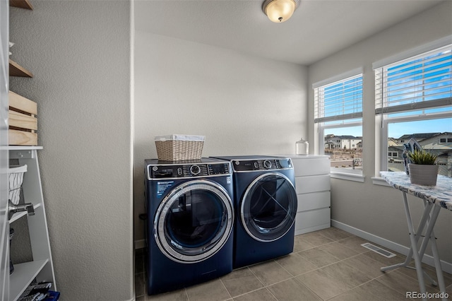 laundry area featuring washing machine and clothes dryer, visible vents, baseboards, light tile patterned floors, and laundry area