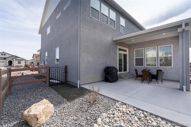 back of house with stucco siding, a gate, entry steps, a patio, and fence