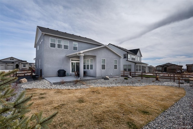 rear view of house with stucco siding, fence, a yard, and a patio area