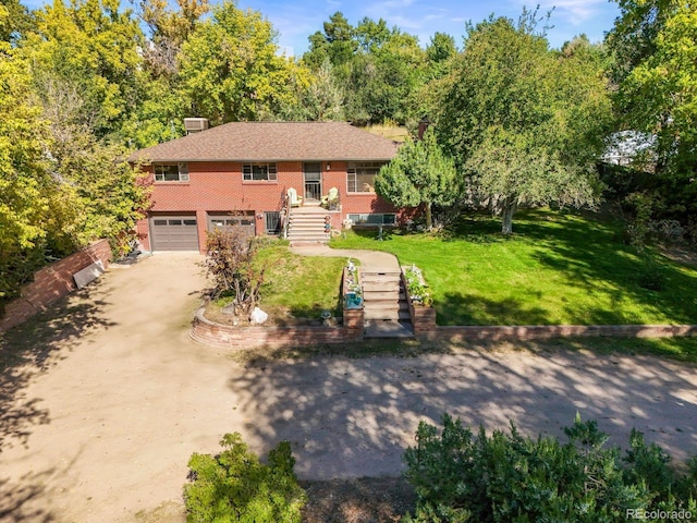 split foyer home with dirt driveway, a garage, a front yard, and brick siding
