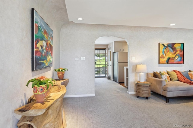 carpeted living area featuring arched walkways, baseboards, and recessed lighting