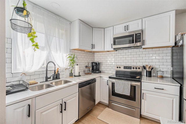 kitchen with light hardwood / wood-style flooring, appliances with stainless steel finishes, sink, and white cabinetry