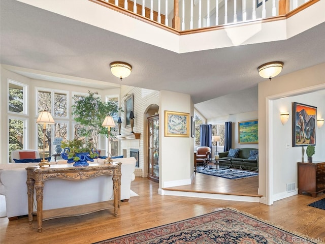 entrance foyer featuring a brick fireplace, a healthy amount of sunlight, and light wood-style flooring