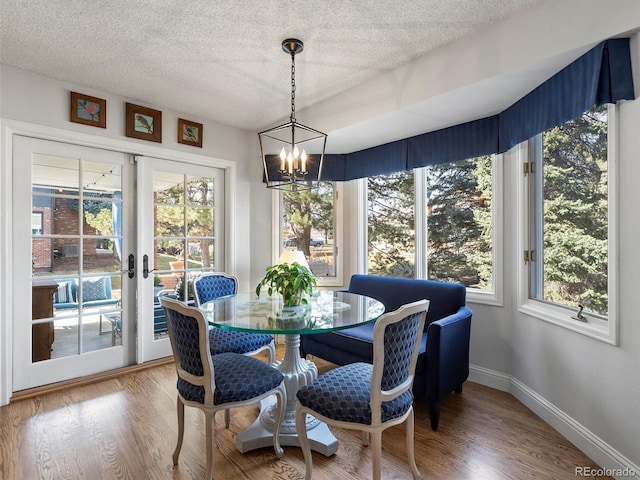 sunroom / solarium featuring a healthy amount of sunlight, an inviting chandelier, and french doors