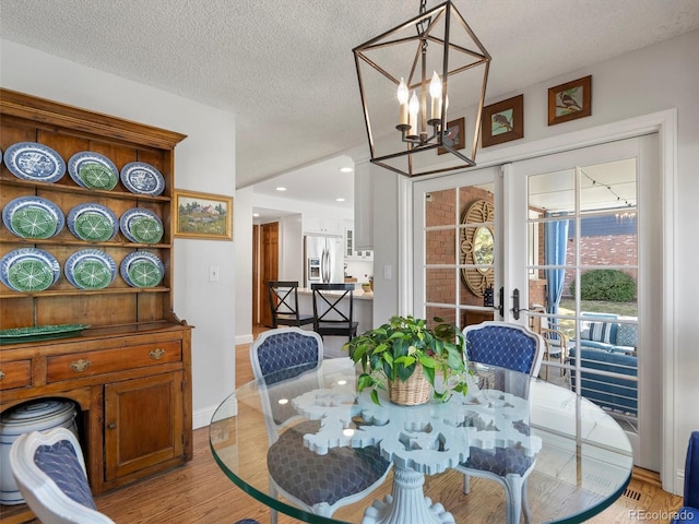 dining area with a chandelier, a textured ceiling, recessed lighting, baseboards, and light wood-type flooring