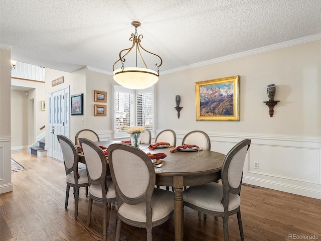 dining area with stairway, crown molding, a textured ceiling, and wood finished floors