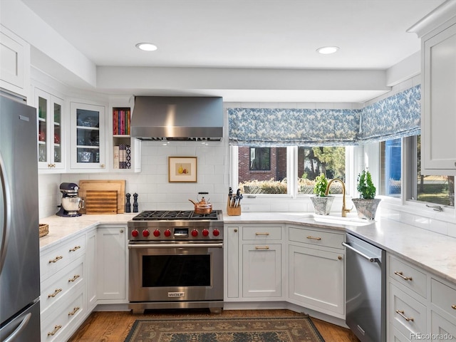 kitchen with glass insert cabinets, appliances with stainless steel finishes, white cabinets, and exhaust hood