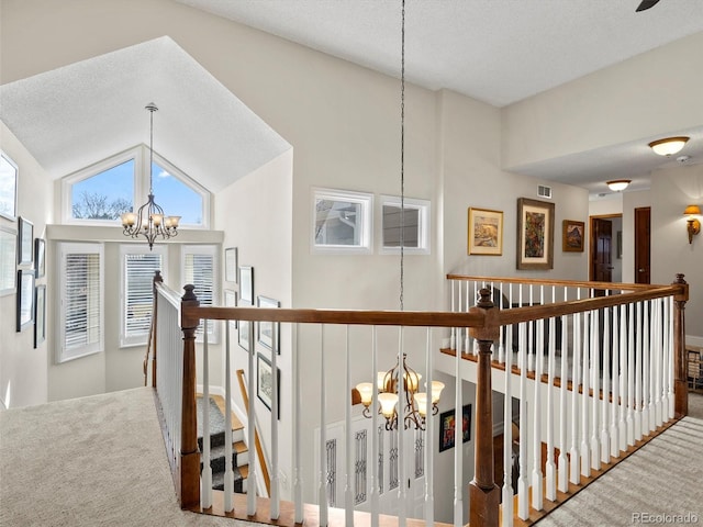 corridor featuring visible vents, a chandelier, carpet flooring, and an upstairs landing