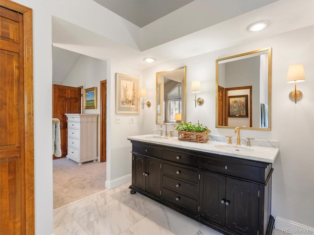 full bath featuring marble finish floor, double vanity, a sink, and baseboards