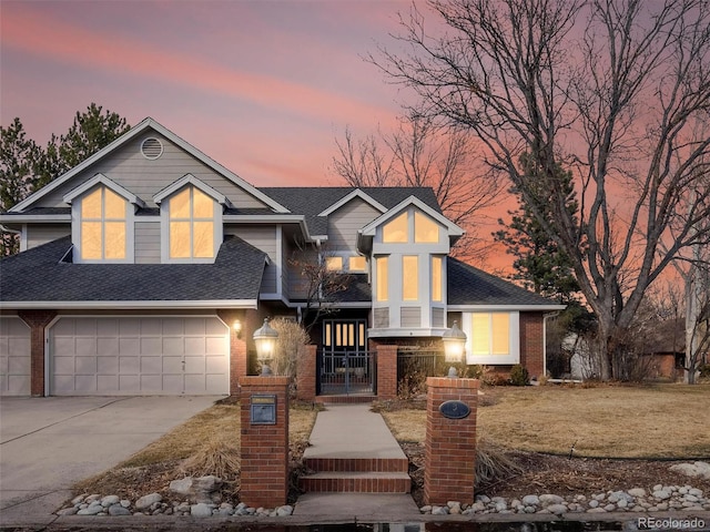 view of front facade with driveway, brick siding, a shingled roof, and a gate