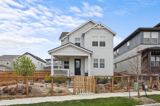 view of front facade with board and batten siding, a porch, and a fenced front yard