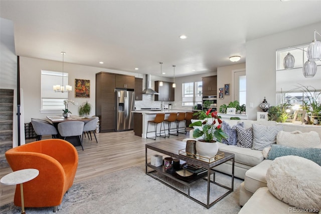 living room featuring stairway, a notable chandelier, light wood finished floors, and recessed lighting