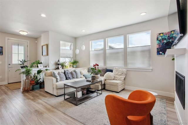 living area featuring baseboards, light wood finished floors, and plenty of natural light