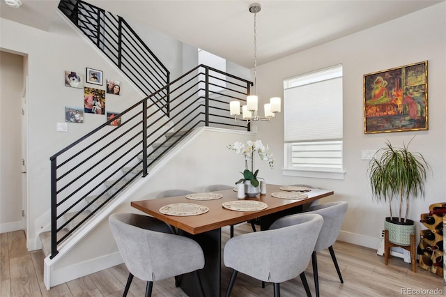 dining area featuring light wood-style flooring, baseboards, a chandelier, and stairway
