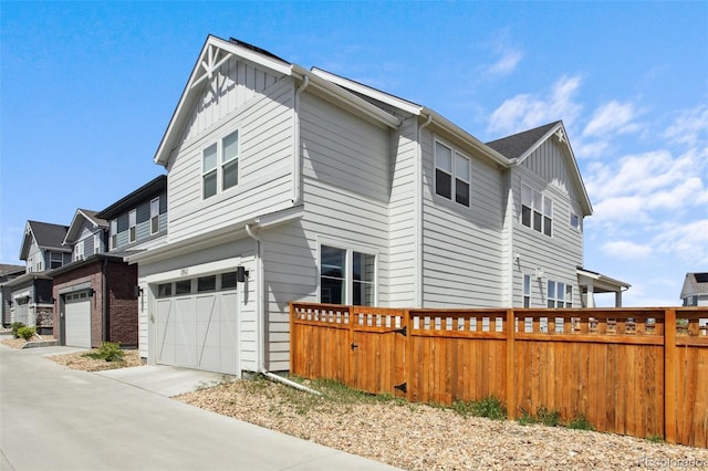 view of property exterior featuring fence, an attached garage, driveway, and board and batten siding