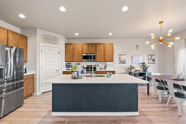 244 Chipeta Way, Lochbuie, CO 80603 - kitchen with stainless steel appliances, a sink, brown cabinetry, light countertops, and light wood-type flooring