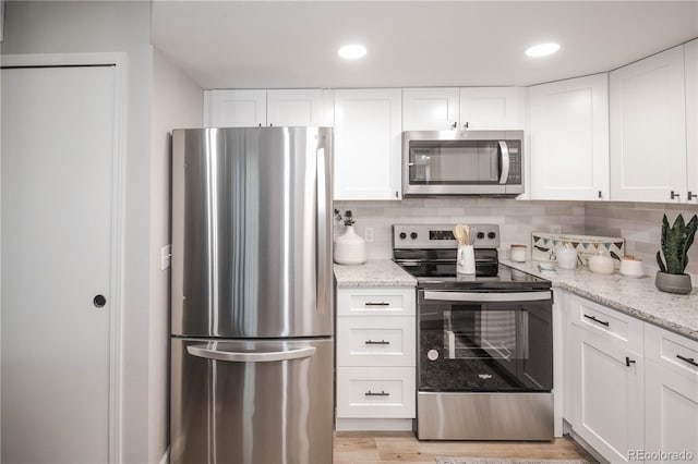 kitchen with white cabinetry, light stone countertops, and appliances with stainless steel finishes