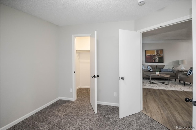 carpeted bedroom featuring a textured ceiling, a walk in closet, and a closet