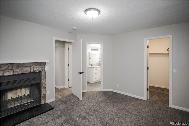 unfurnished living room featuring carpet flooring, a textured ceiling, and a fireplace