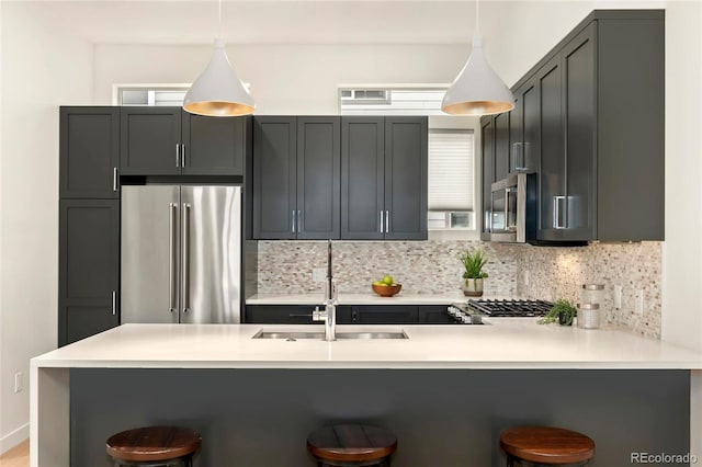 kitchen featuring stainless steel appliances, a breakfast bar, pendant lighting, and kitchen peninsula