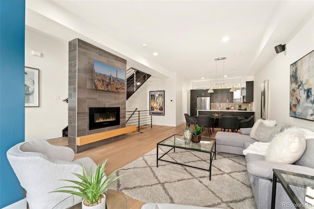 living room with a tiled fireplace and light hardwood / wood-style flooring