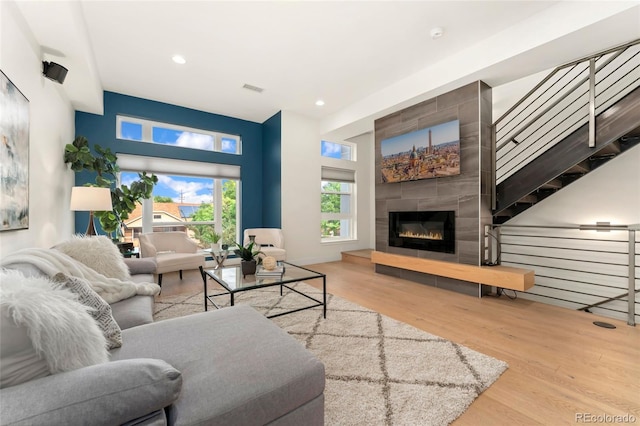 living room with a tiled fireplace and light hardwood / wood-style floors