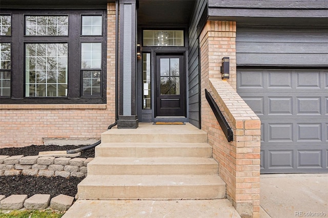 doorway to property with brick siding and a garage