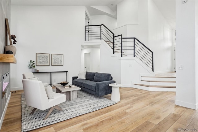 living room with stairway, baseboards, a high ceiling, and wood finished floors