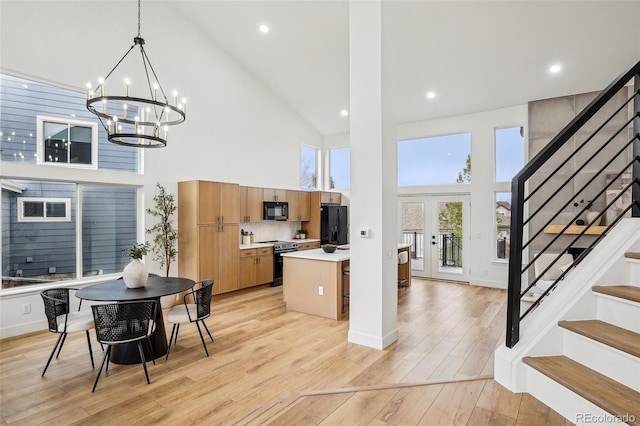 kitchen with a notable chandelier, light countertops, high vaulted ceiling, light wood-style flooring, and black appliances