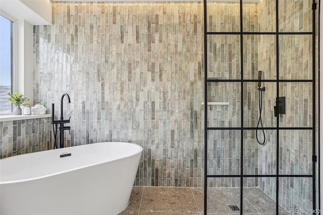 full bath with a freestanding tub, tile walls, and walk in shower