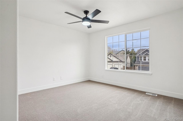 carpeted empty room featuring baseboards, visible vents, and ceiling fan