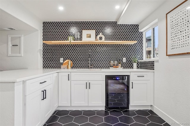 bar featuring beverage cooler, a sink, decorative backsplash, and indoor wet bar