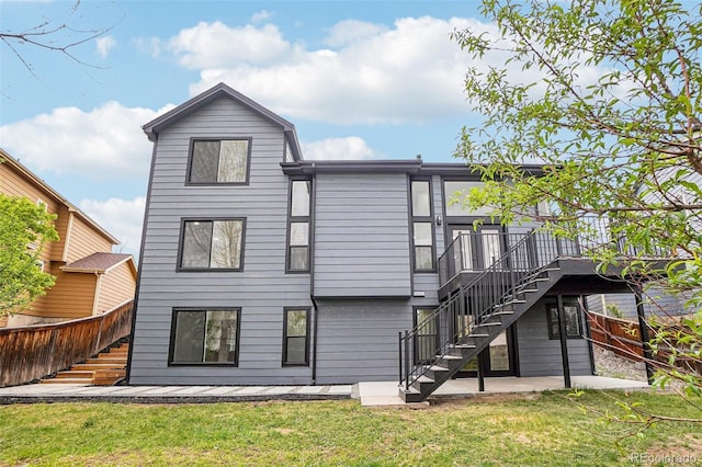 rear view of property featuring a wooden deck, stairway, fence, a yard, and a patio