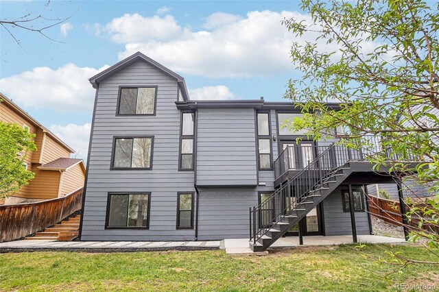 1057 English Sparrow Trl, Highlands Ranch, CO 80129 - rear view of property featuring a wooden deck, stairway, fence, a yard, and a patio