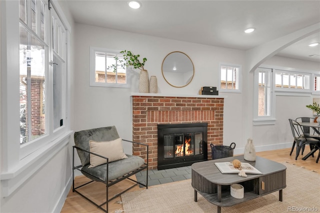 living room with light wood-type flooring and a brick fireplace