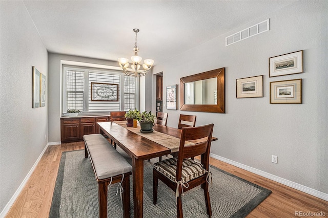 10994 Shadowbrook Cir, Highlands Ranch, CO 80130 - dining space with a chandelier, light wood-style floors, and a textured wall