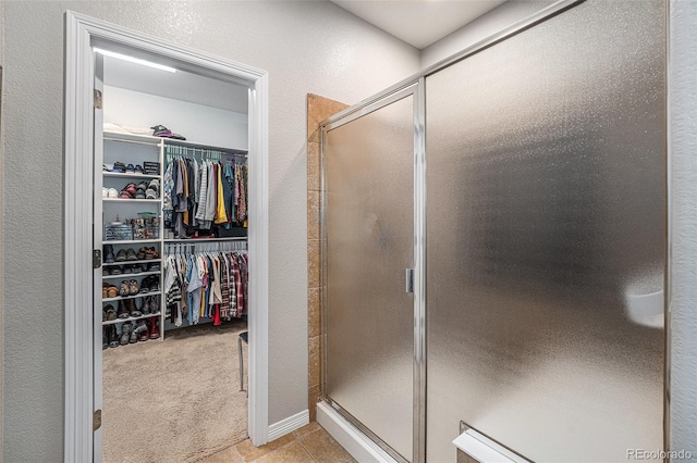 10994 Shadowbrook Cir, Highlands Ranch, CO 80130 - bathroom with a stall shower, a walk in closet, a textured wall, and tile patterned floors