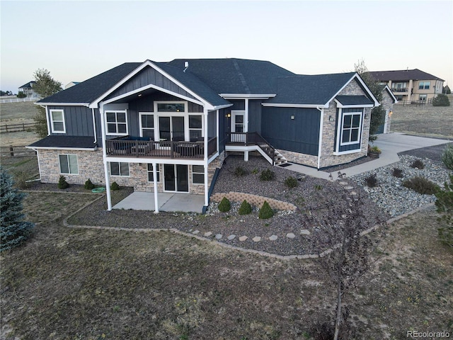 back house at dusk featuring a patio and a deck