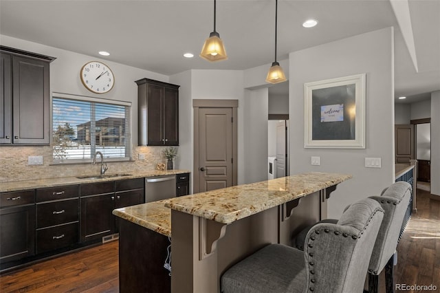 kitchen featuring pendant lighting, dishwasher, a center island, backsplash, and sink