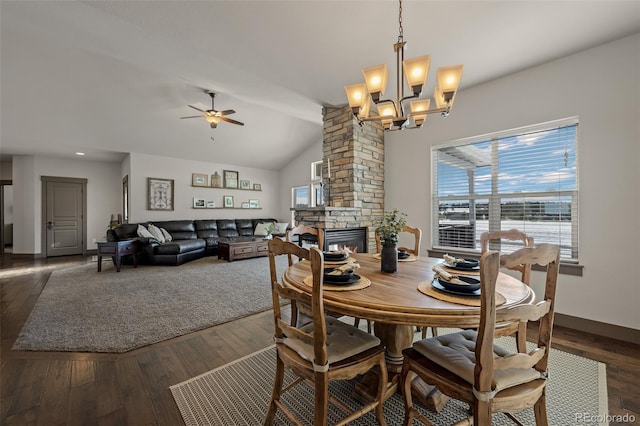 dining area with vaulted ceiling, a fireplace, ceiling fan with notable chandelier, and dark hardwood / wood-style floors