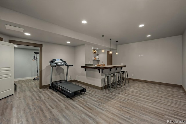 workout room featuring light wood-type flooring and bar area