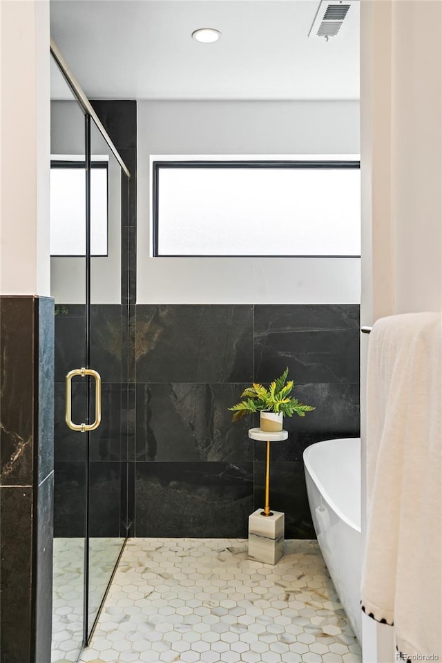 bathroom featuring tile patterned floors, tile walls, and shower with separate bathtub