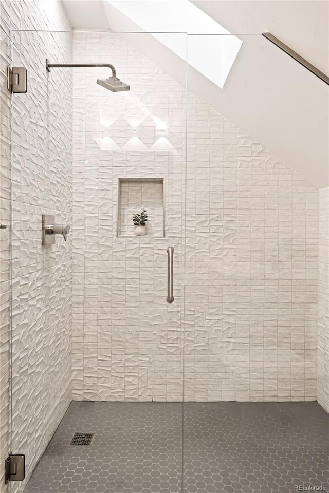 bathroom featuring lofted ceiling with skylight and an enclosed shower