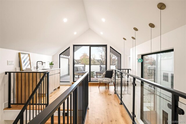 hallway featuring light hardwood / wood-style floors, sink, and vaulted ceiling