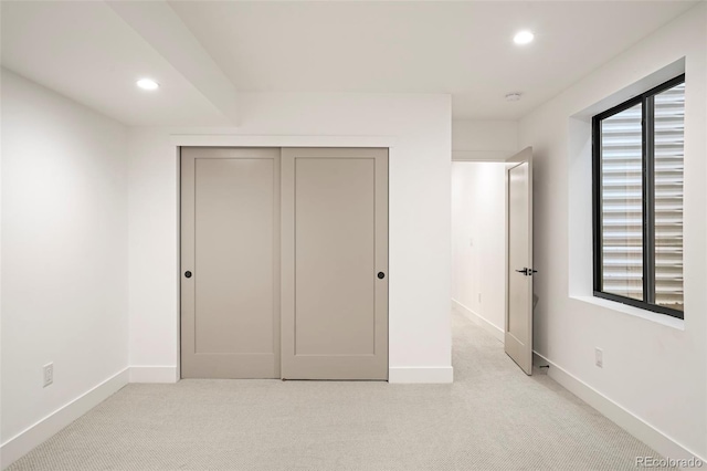 unfurnished bedroom with a closet and light colored carpet