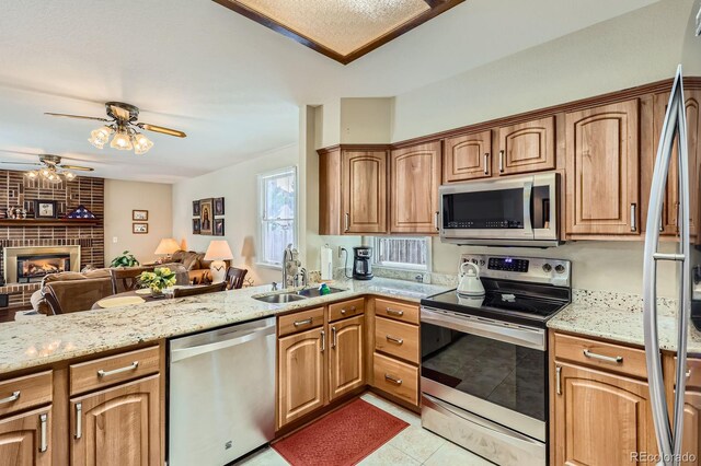 6376 S Pierson St, Littleton, CO 80127 - kitchen featuring appliances with stainless steel finishes, a sink, open floor plan, a ceiling fan, and light stone countertops