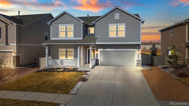 traditional home with fence, a porch, concrete driveway, a garage, and stone siding