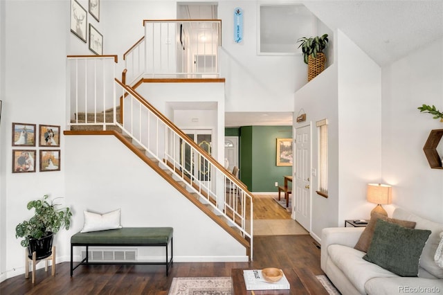 stairway with hardwood / wood-style floors and a high ceiling