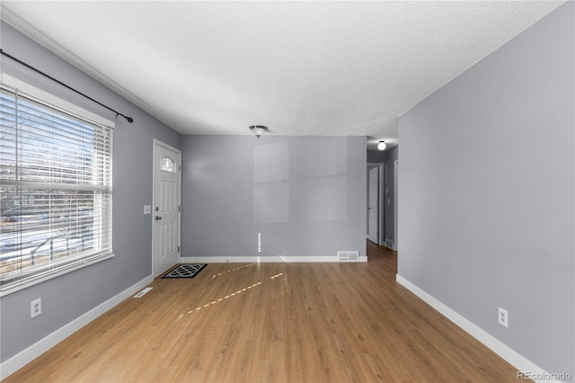 unfurnished living room with light hardwood / wood-style floors and a textured ceiling