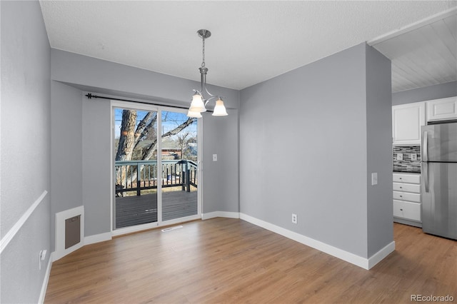 unfurnished dining area with an inviting chandelier and light hardwood / wood-style floors